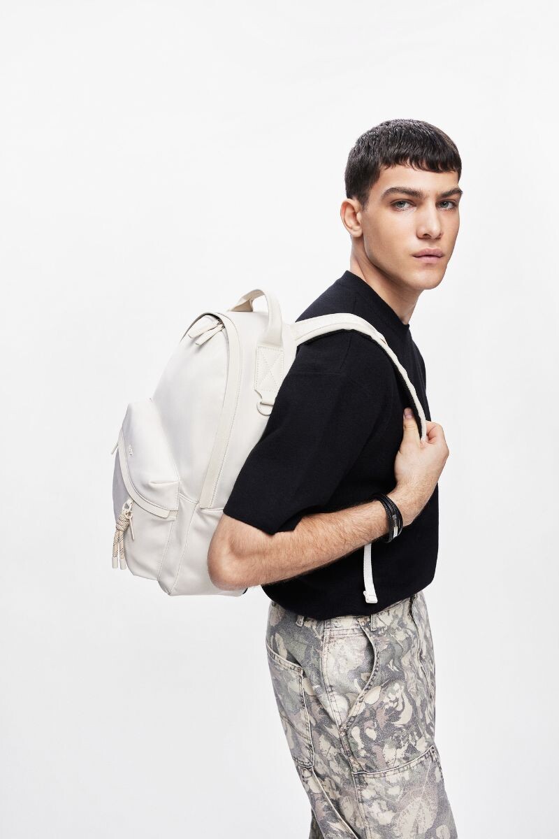 young man carrying a white backpack and faded pants