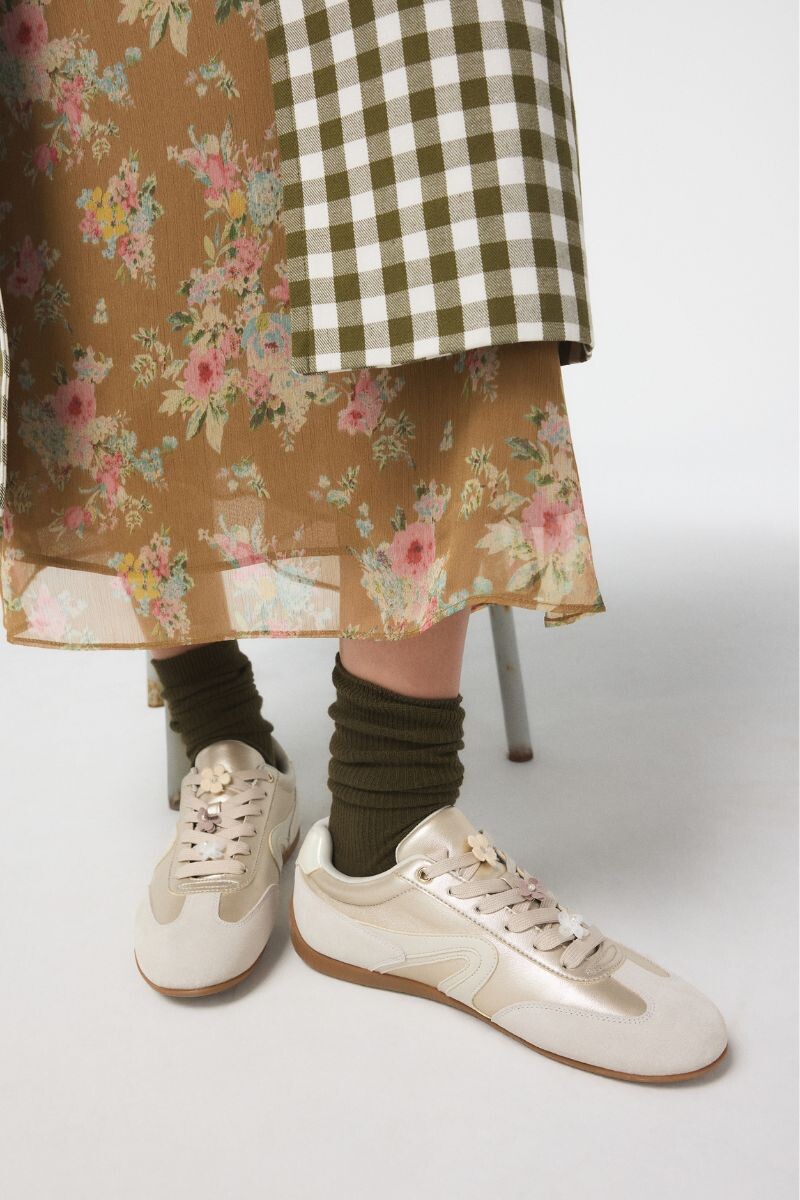 Gold sneakers with floral detail and rubber sole.