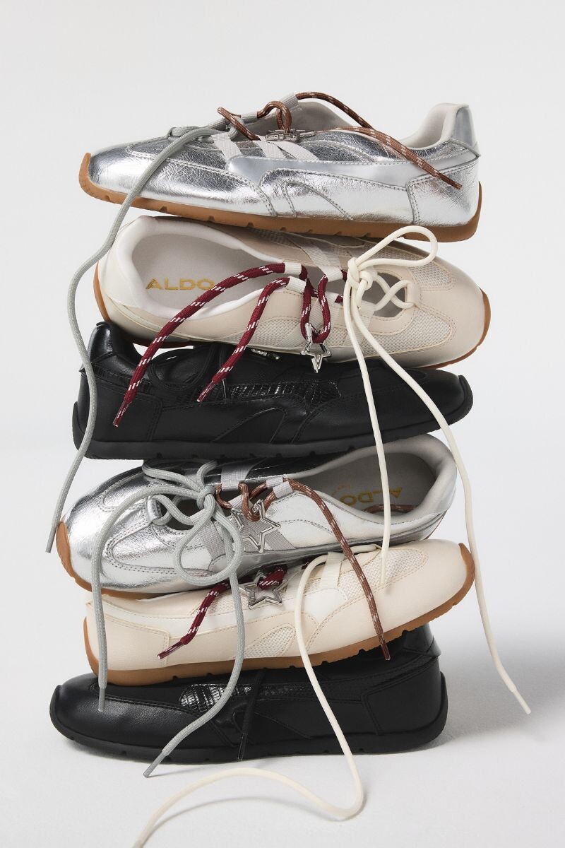 Stacked sneakers in black, beige, and silver.
