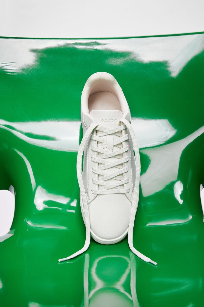 View from above of white men's sneakers on a green chair