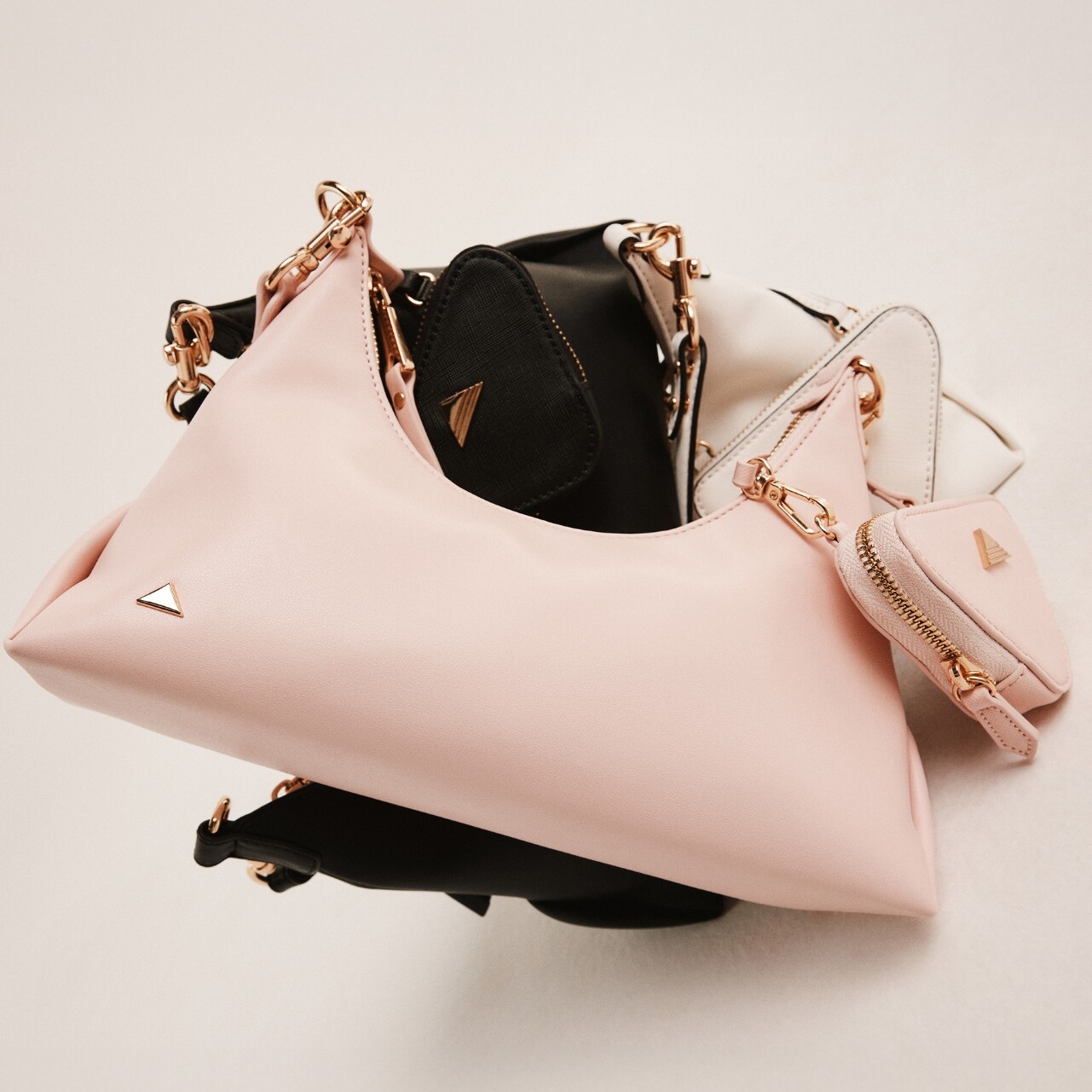 Bolsos en rosa, negro y blanco con bolsa triangular.