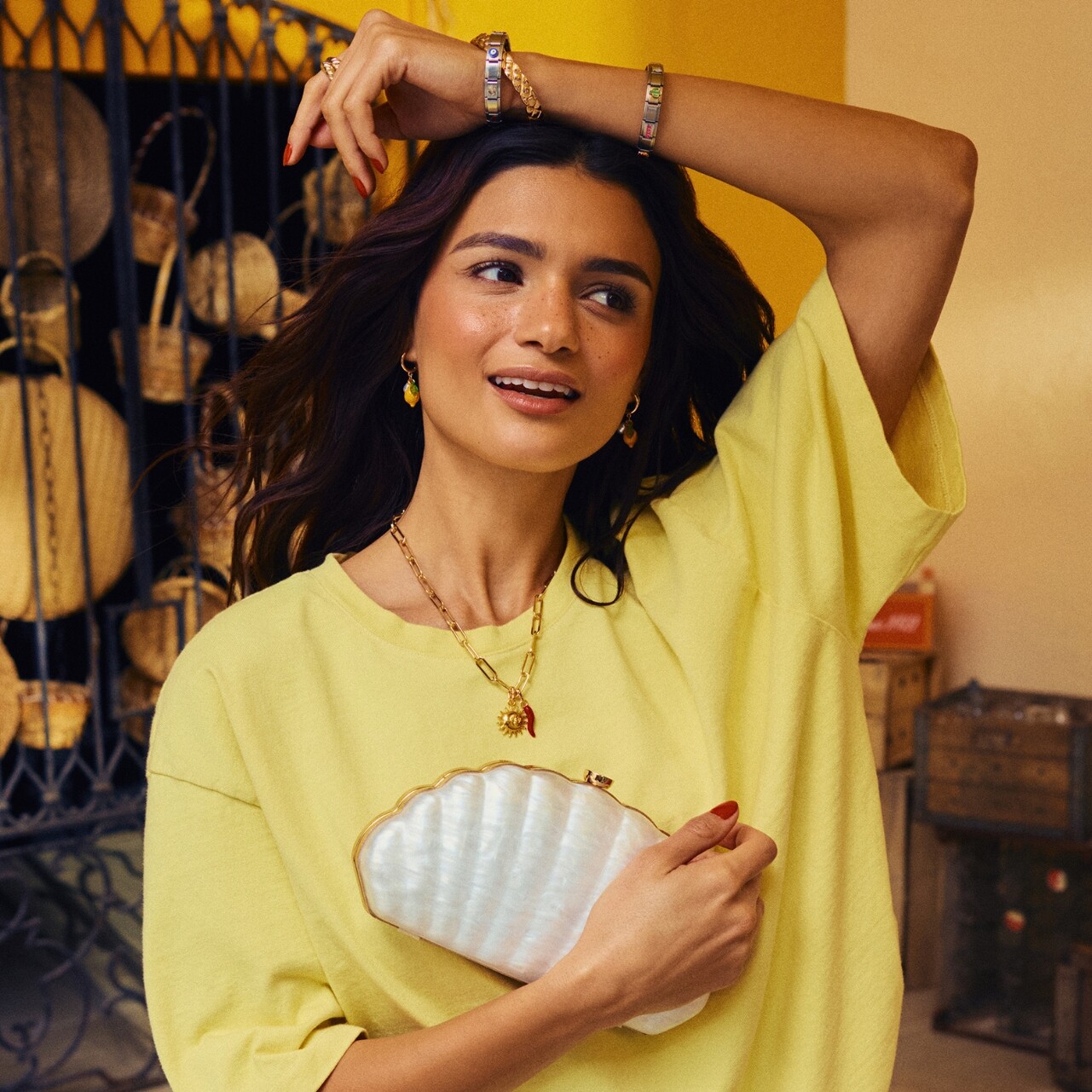 Mujer con vestido amarillo y bolso de mano en forma de concha.