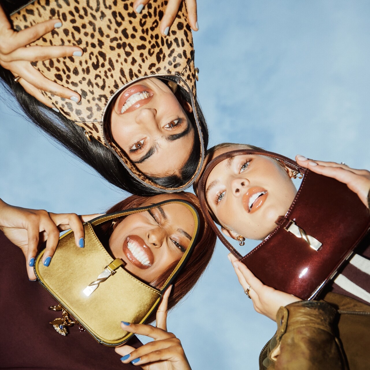 Tres mujeres con bolsos coloridos sonriendo.