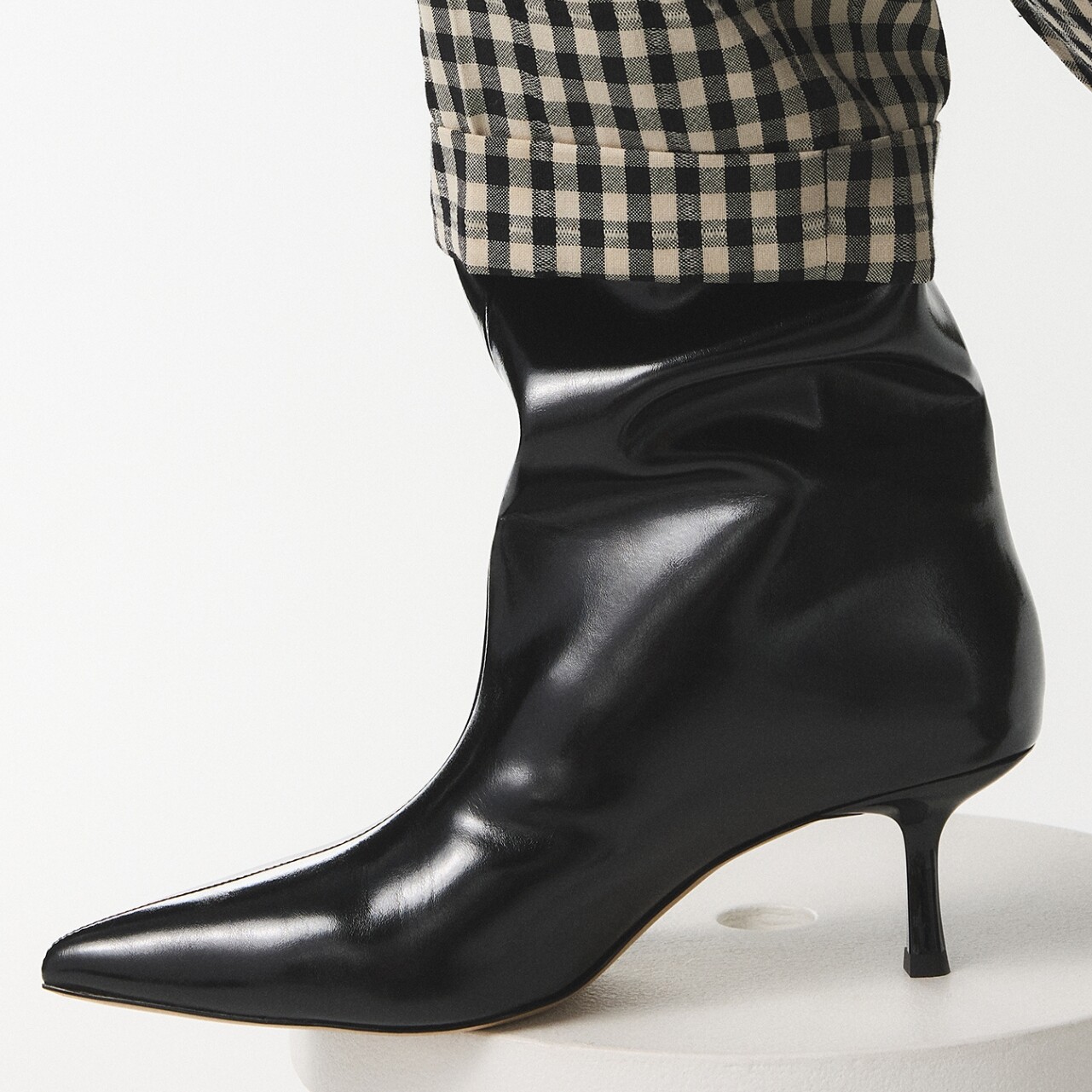 Bota negra de piel con tacón medio y pantalón de cuadros.