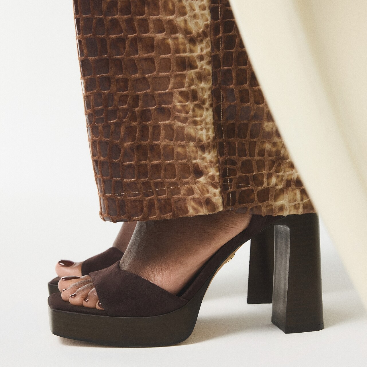 Sandalias de tacón alto ALDO en marrón combinadas con pantalón texturizado.