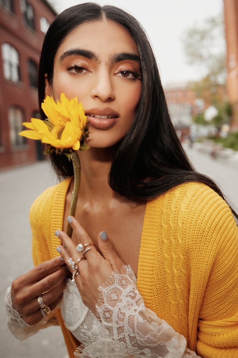 Mujer con cárdigan amarillo y anillos dorados.