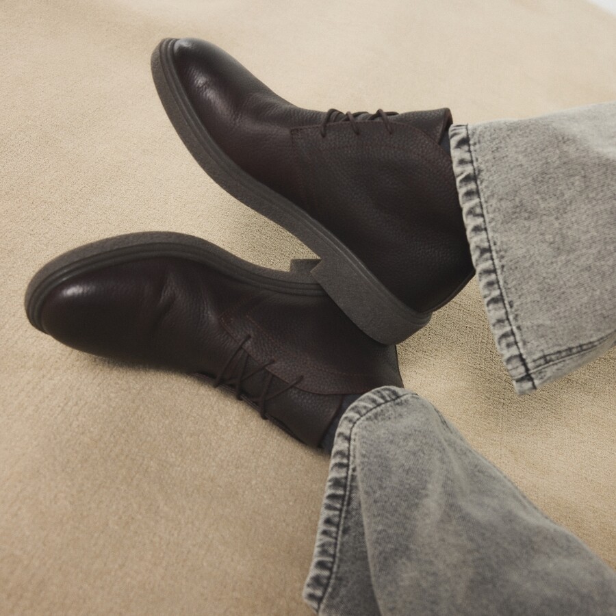 Zapatos marrón oscuro de piel, estilo informal, combinados con vaqueros grises.