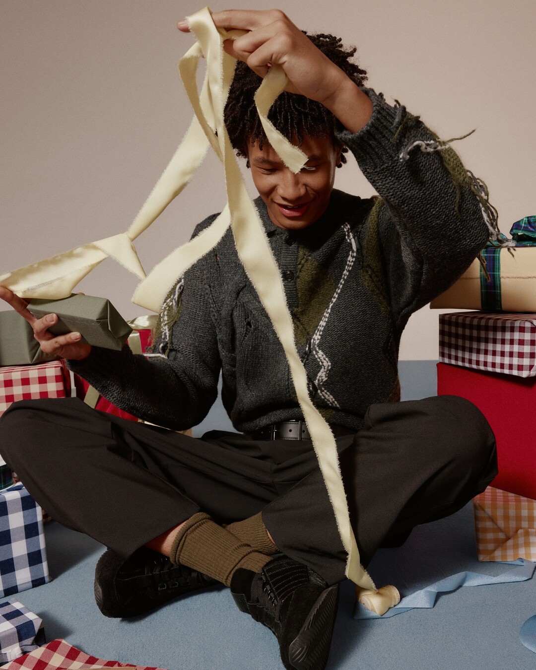 Hombre sentado abriendo regalos, con zapatillas deportivas negras.