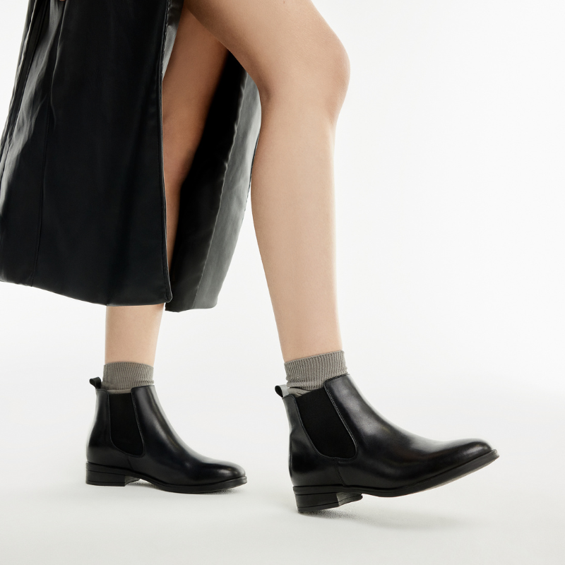 pormenor de pernas de mulher a caminhar com botins rasos em cor preta