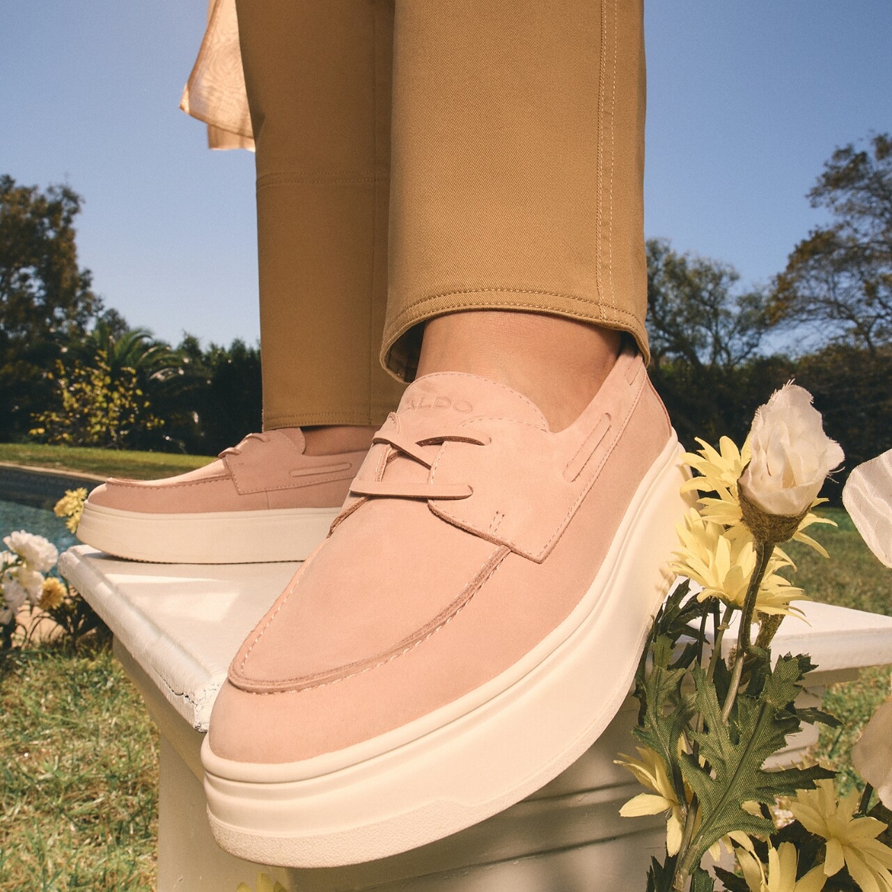 Pé de mulher calçada com sapatos cor de rosa, num ambiente floral.