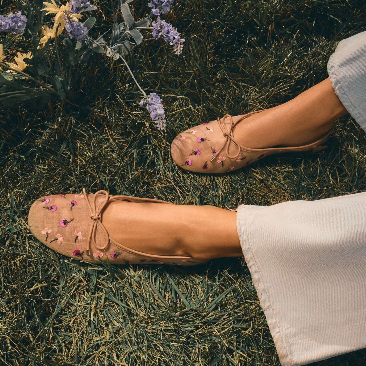 Pies de mujer con zapatos planos rosas con motivos florales.