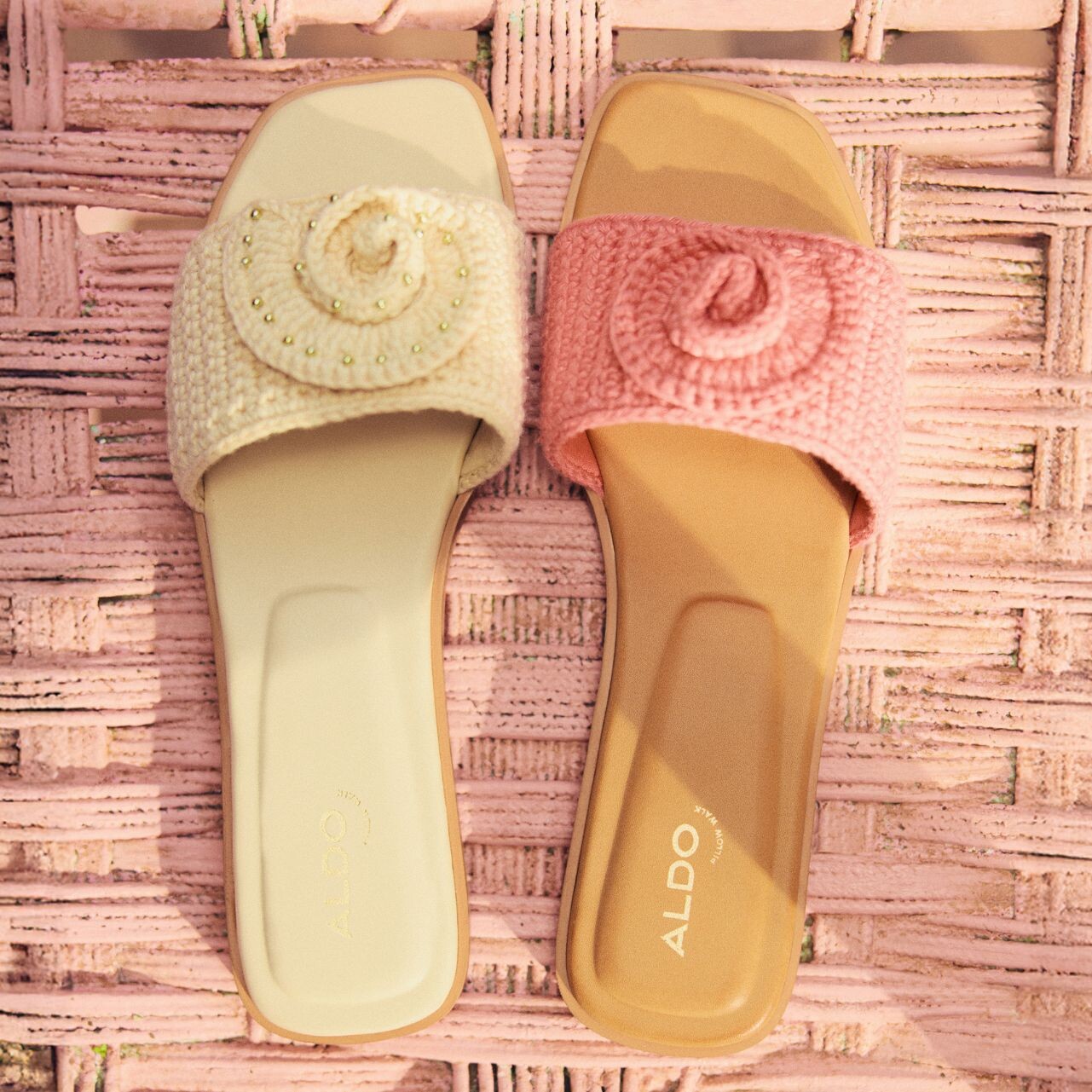 Sandalias planas de varios colores con detalles de crochet, apoyadas en una cesta rosa.