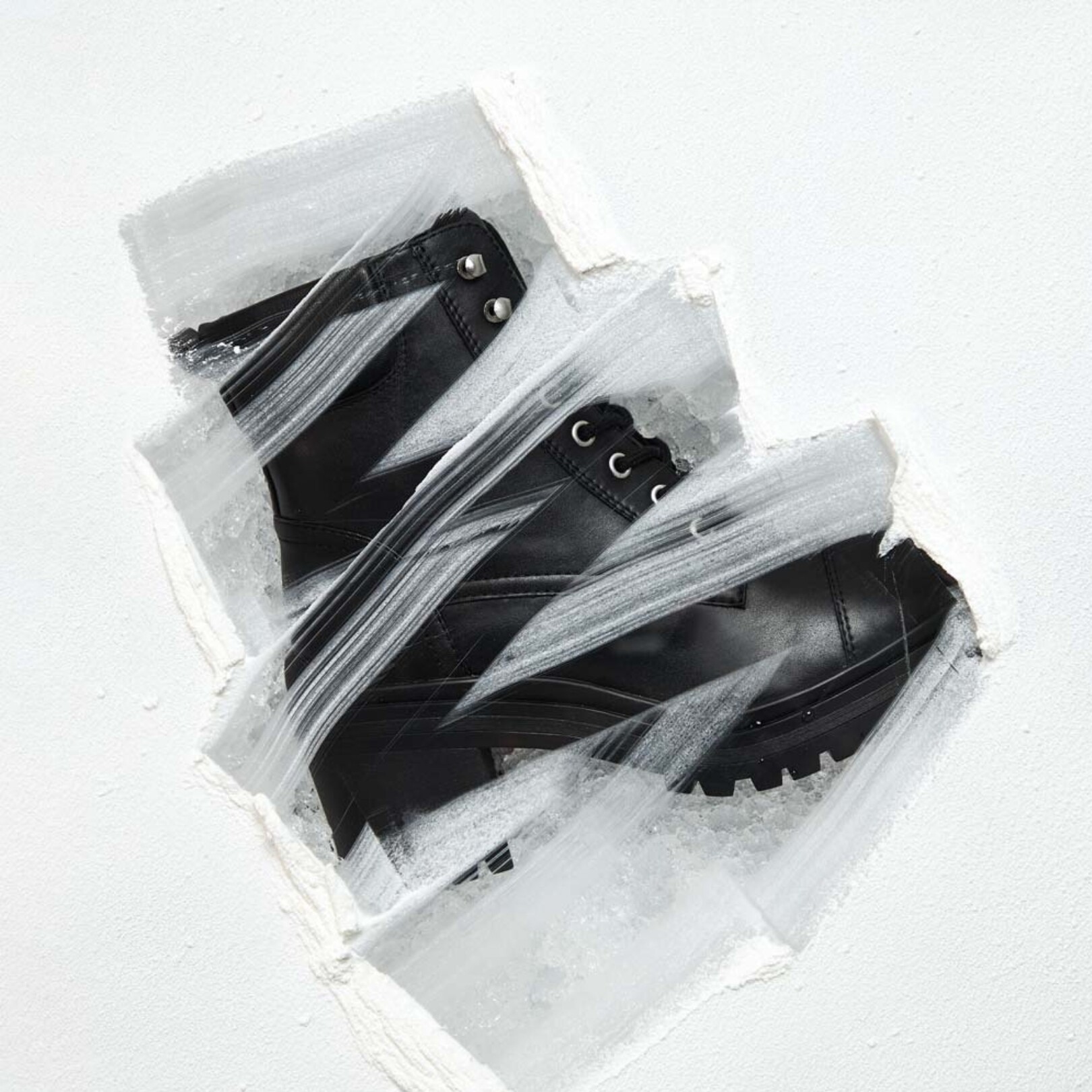 Botín negro con tacón, posado sobre hielo.