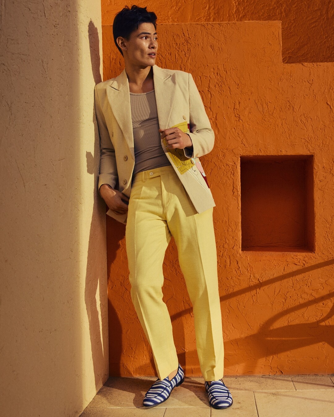 Hombre con blazer beige y mocasines de rayas azules.