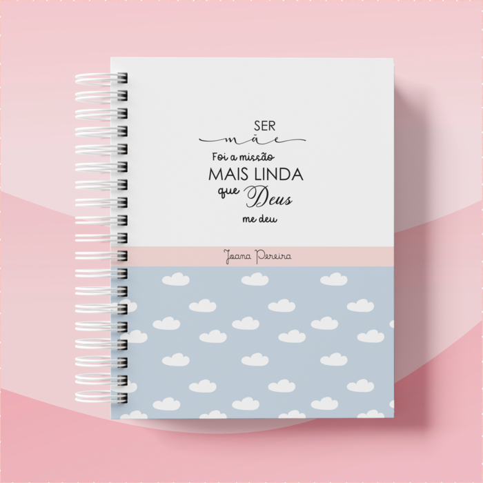 Caderno espiral com metade inferior floral e texto manuscrito em português na metade superior, sobre fundo rosa suave.