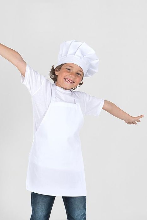 Criança sorridente com chapéu de chef e avental branco, braços abertos