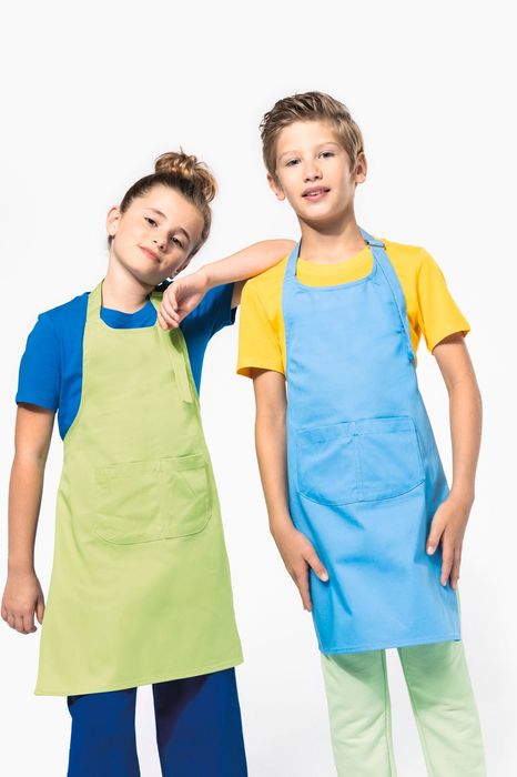 Duas crianças de pé com aventais, menina de avental verde e rapaz de avental azul.