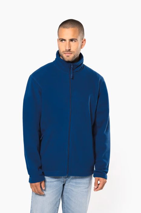 Homem com casaco polar azul de fecho de correr e gola alta, visto de frente ligeiramente virado