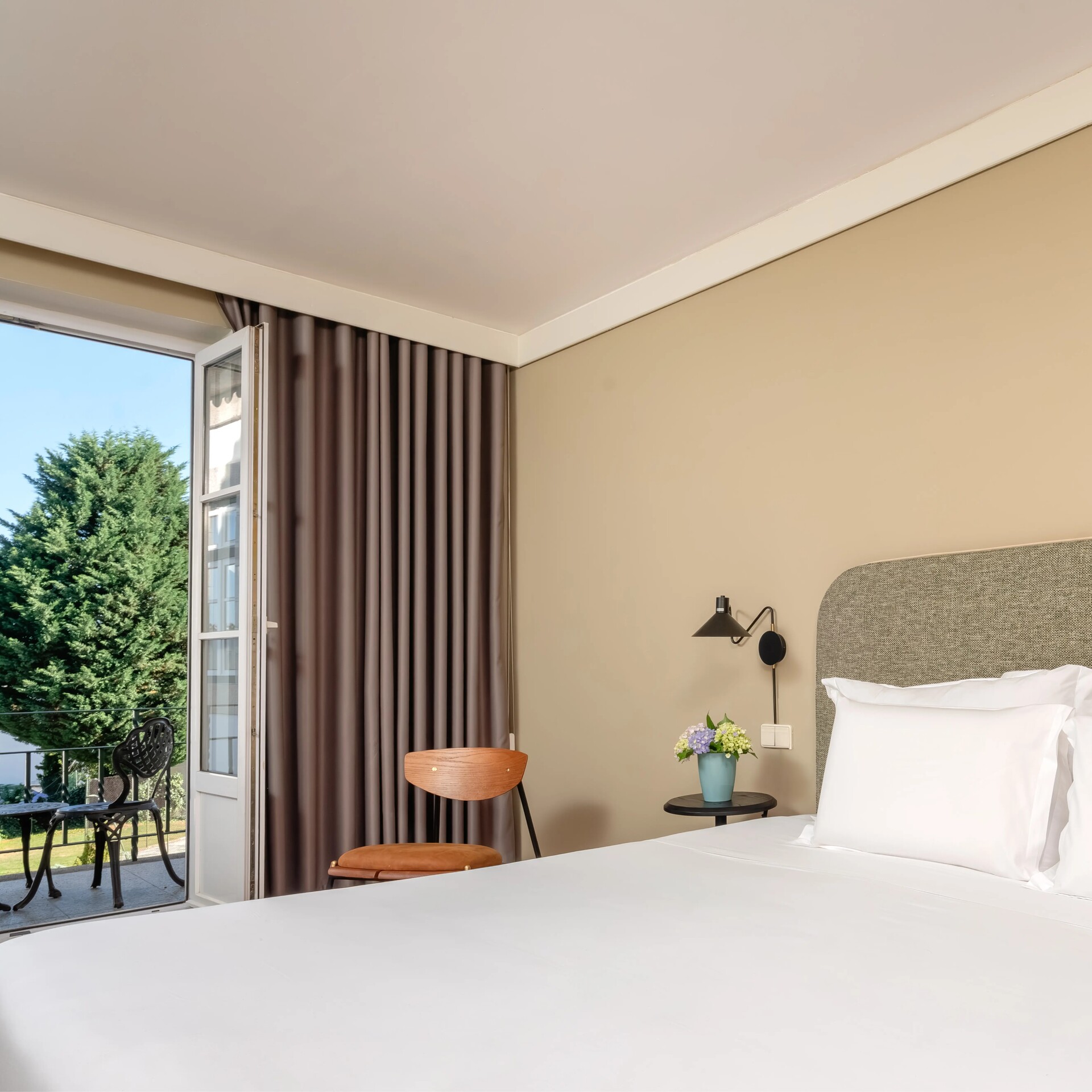 Charming Terrace Room with a plush bed, bedside table with flowers, and warm neutral decor.