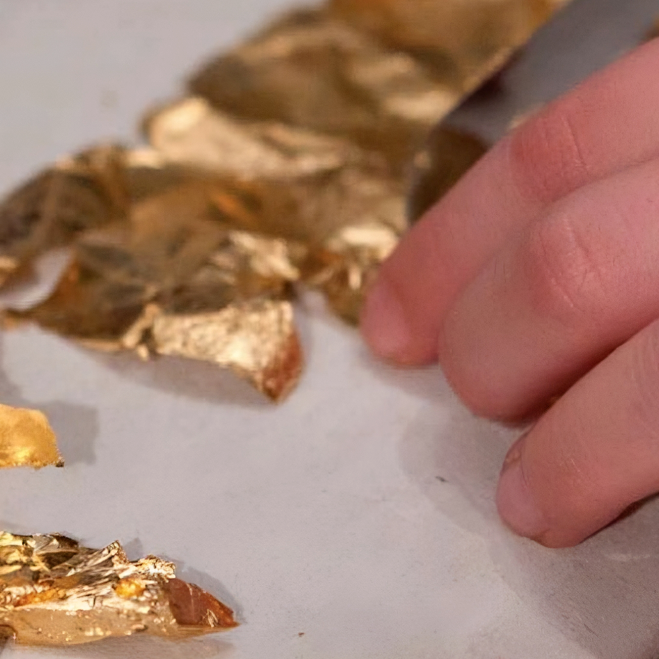 Artisan applying gold leaf to a furniture surface using traditional gilding techniques