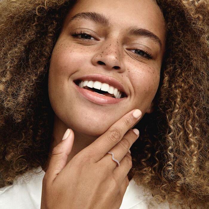 Modelo feminino com um anel rose gold da Pandora cravado de zircónias e com um efeito ondulado.