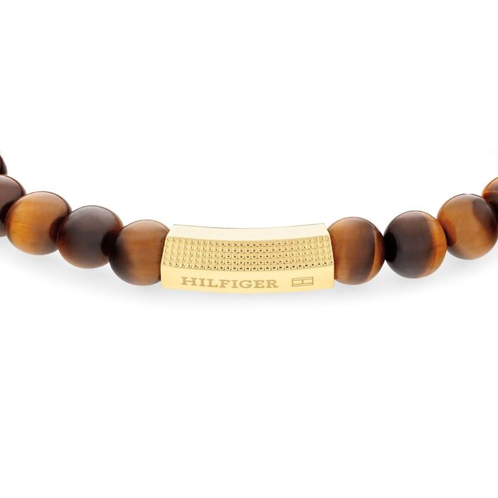 Detalhe da peça em aço dourado com pedras naturais olho de tigre de uma pulseira Tommy Hilfiger.