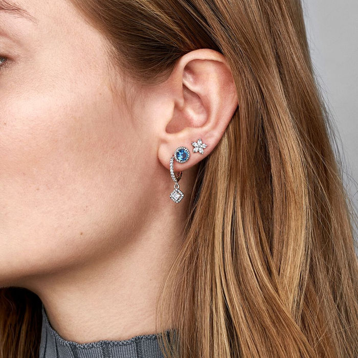 Modelo com três diferentes brincos prateados da Pandora com zircónias incolores e uma azul.
