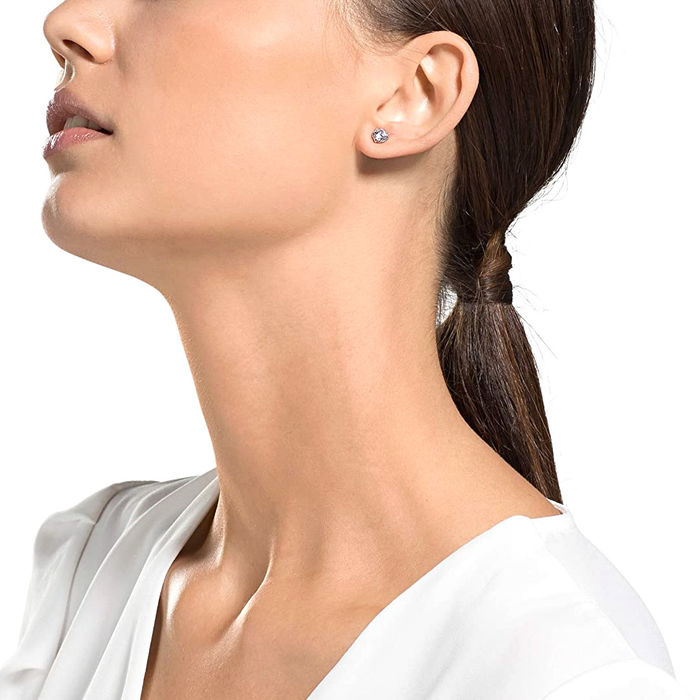 Modelo feminino com um brinco prateado com um cristal Swarovski circular engastado em garras.