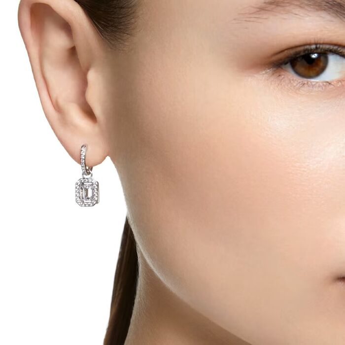 Modelo com uma argola prateada Swarovski com um pendente octogonal com cristais e uma pedra incolor.