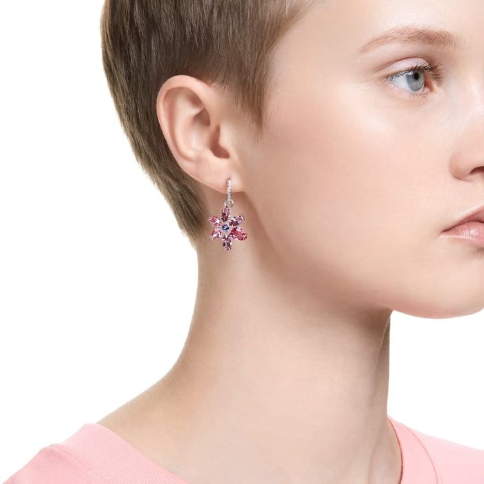 Modelo feminino com uma argola prateada Swarovski com uma flor com as pétalas em cristais rosas.