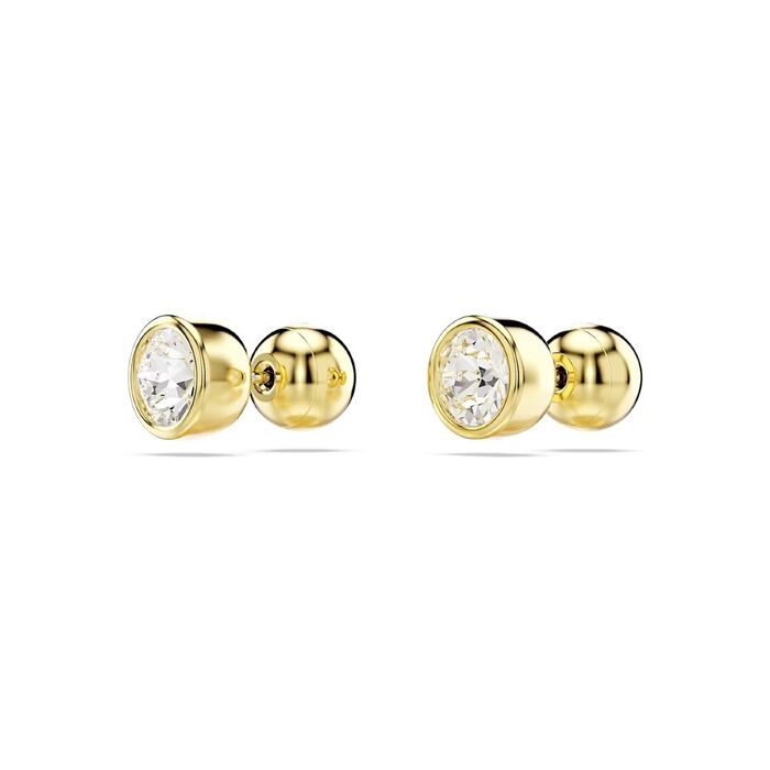 Brincos dourados Swarovski, de lado, com um cristal incolor circular em cada peça.