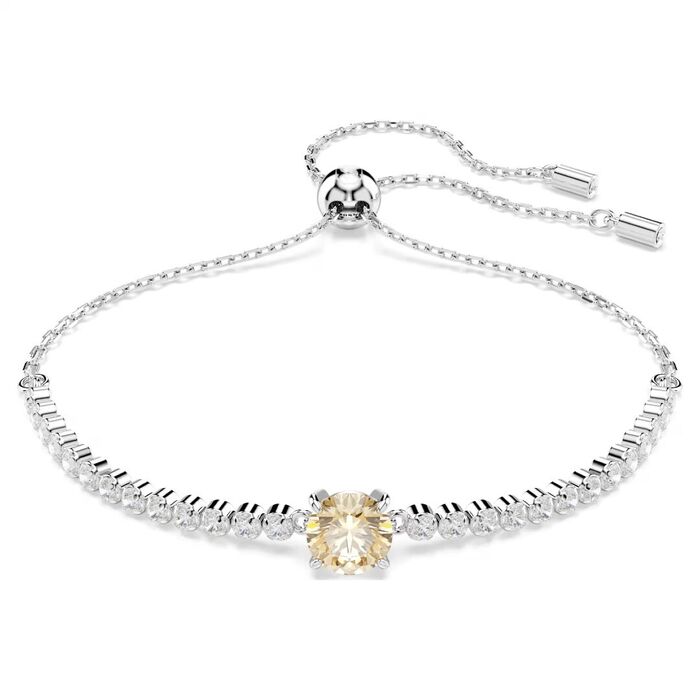 Pulseira prateada Swarovski com cristais incolores e com uma pedra amarela circular no centro.