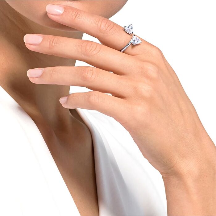 Modelo feminino com um anel prateado Swarovski na vertical cravado de cristais incolores.