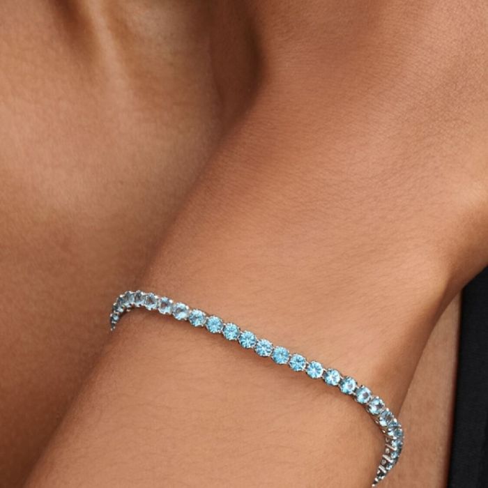 Modelo com uma pulseira Pandora prateada com uma malha preenchida de zircónias azuis.