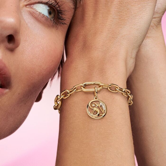 Modelo com uma conta Pandora dourada de um pendente circular com elementos polidos ou com zircónias.