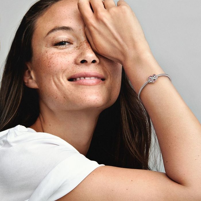 Modelo com uma conta Pandora prateada de um coração zircónias vermelhas e o símbolo infinito.