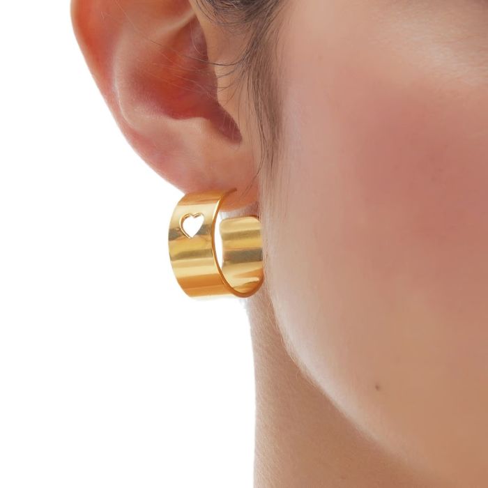 Modelo com argola Victoria Cruz em prata banhada a ouro amarelo 18kl com um recorte em coração.