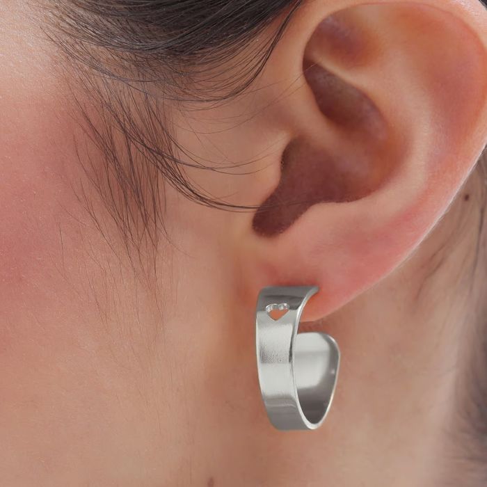 Modelo com uma argola Victoria Cruz em prata com um recorte em forma de coração no topo da joia.