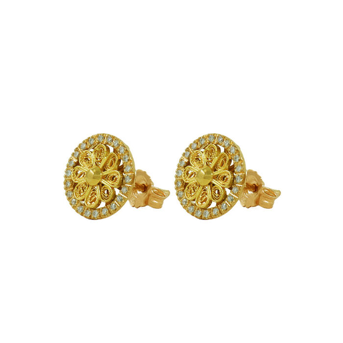 Vista lateral de brincos ouro amarelo, em forma de círculo com flor filigrana e diamantes ao redor.