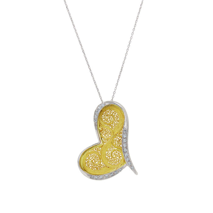 Vista aproxima de pendente em colar feminino de ouro branco, em forma de coração em filigrana.