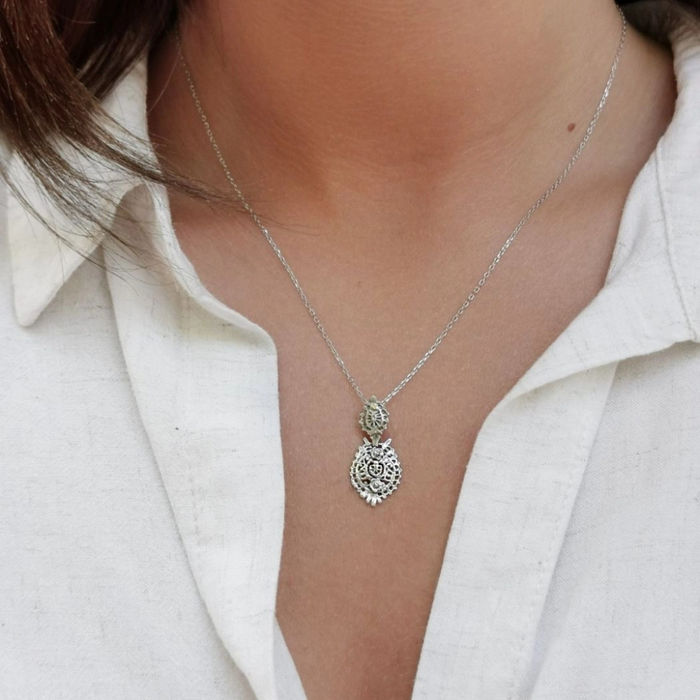 Modelo feminino com um colar prateado da Portugal Jewels com um pendente em estilo brinco à Rainha.