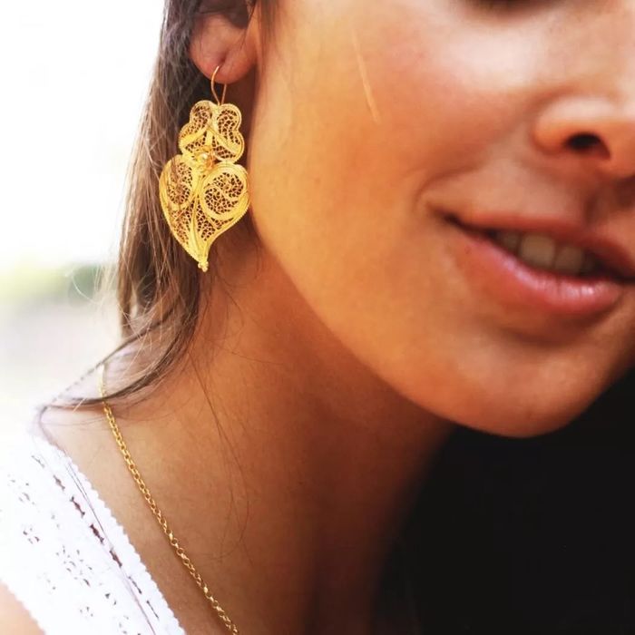 Modelo com um brinco dourado em filigrana da Portugal Jewels com a forma de um coração de viana.