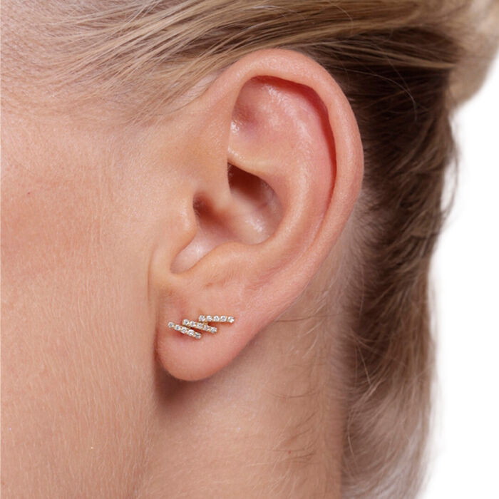 Modelo com brinco LECARRÉ em ouro amarelo com diamantes cravados em 3 barras, efeito de earcuff.