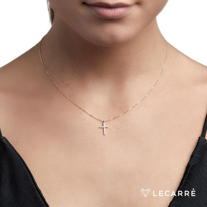 Mulher com colar Lecarré em ouro amarelo de malha fina, com cruz pendente cravada de diamantes.