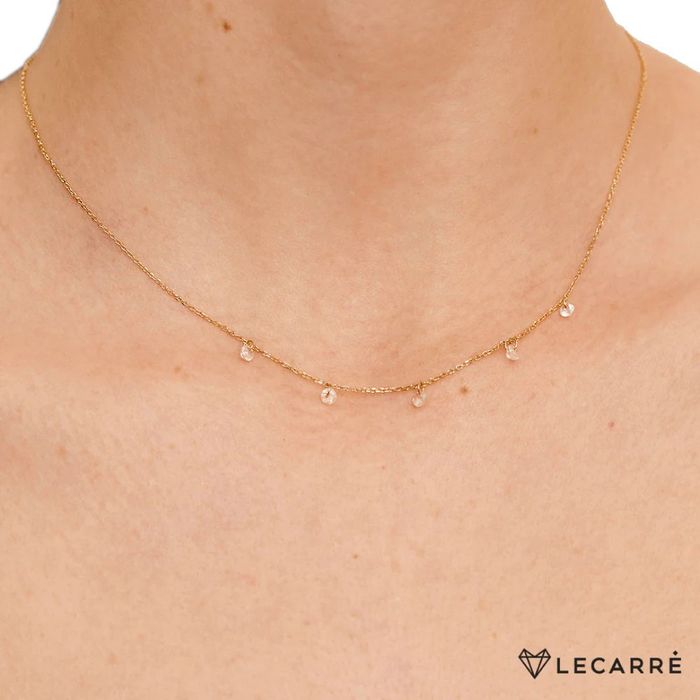 Modelo feminina com colar em ouro amarelo de dezoito quilates, com cinco topázios brancos pendentes.