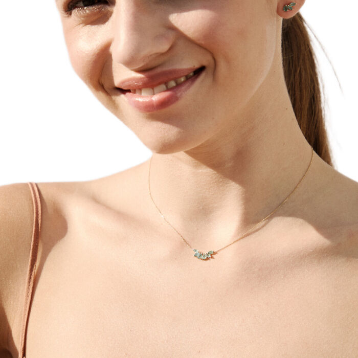 Modelo feminina com colar feminino em ouro amarelo, com seis esmeraldas juntas, pendentes sob o fio.