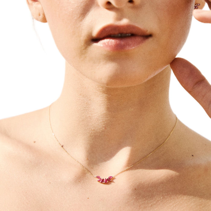 Modelo com colar feminino Lecarré em ouro amarelo, com seis rubis juntos, pendentes sob o fio.