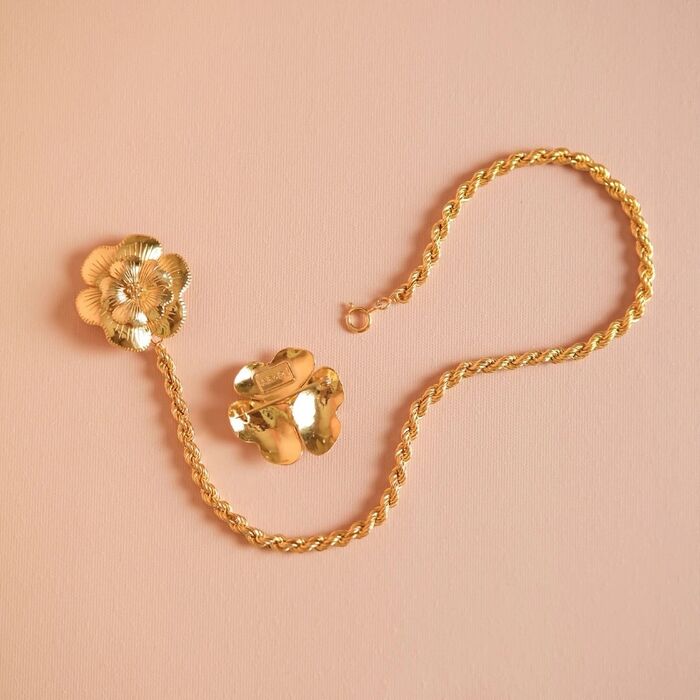 Alfinete dourado Portugal Jewels com uma flor ligada a um fio de malha em corda e outra seperada.