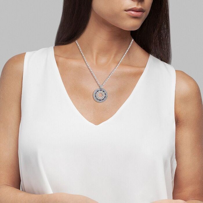 Modelo a usar um fio com uma medalha Tashi com zircónias e pedras azuis juntas de uma linha dourada.