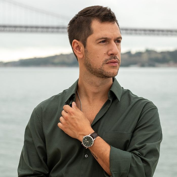 Modelo masculino com relógio One de bracelete em pele castanha e com mostrador verde com calendário.